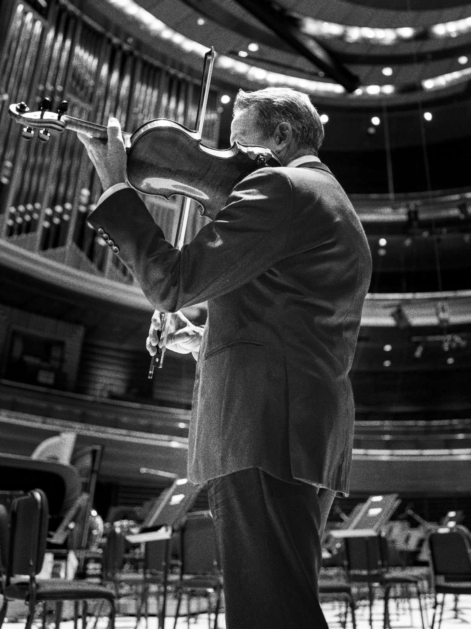 Richard Amoroso playing violin in a black-and-white concert hall photograph