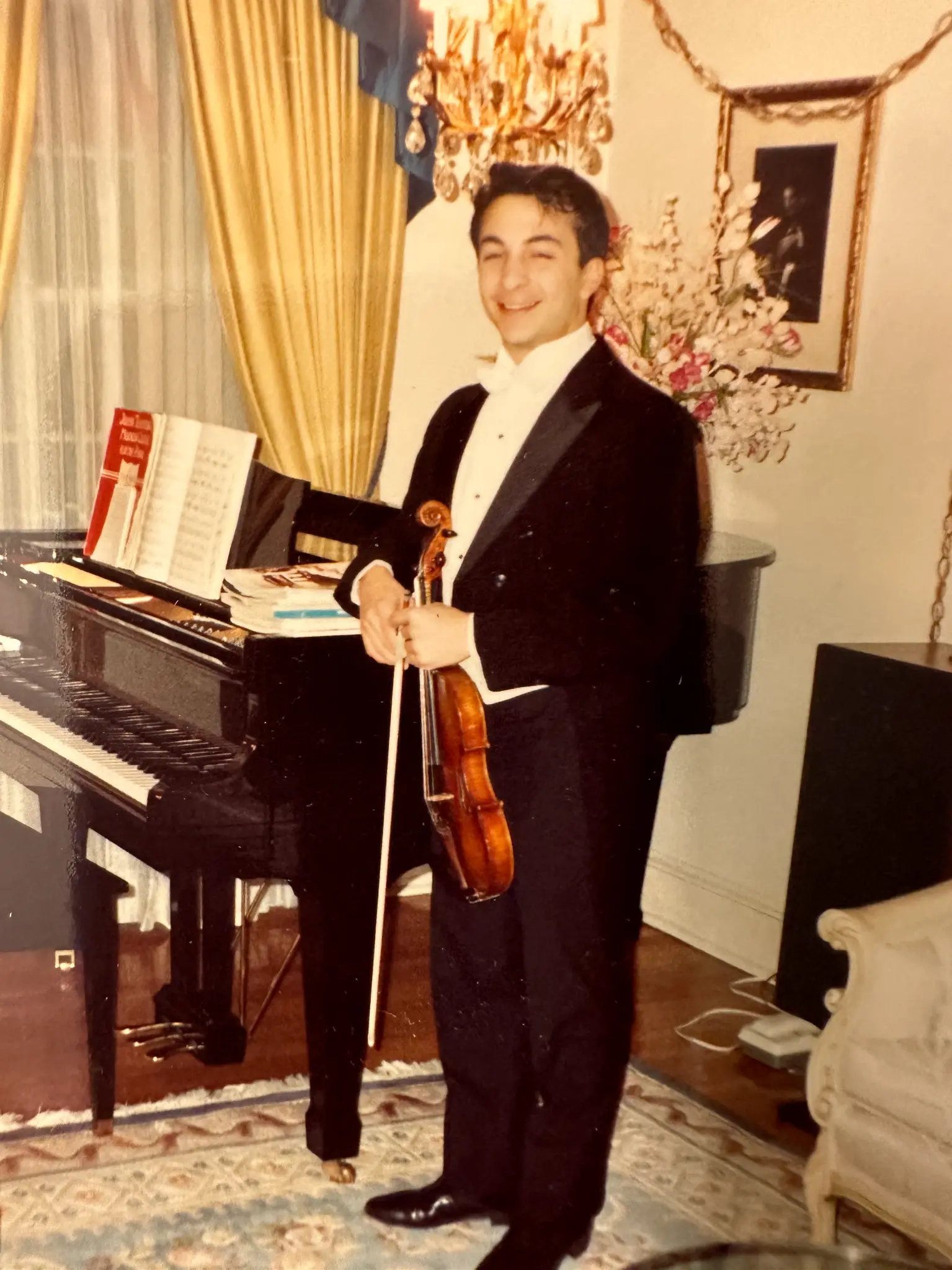 Richard holding his violin beside a piano during his years of musical study